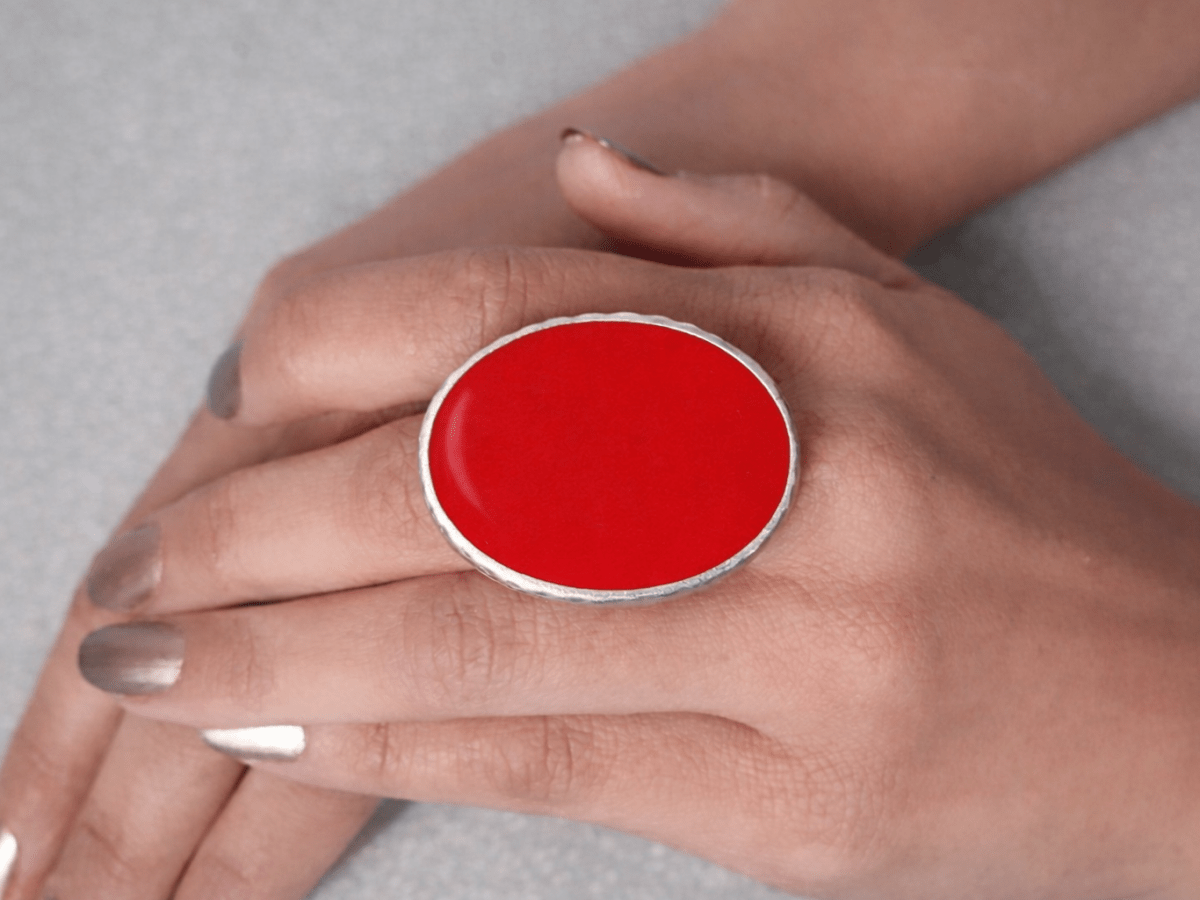 A models hand wearing a red oval ring