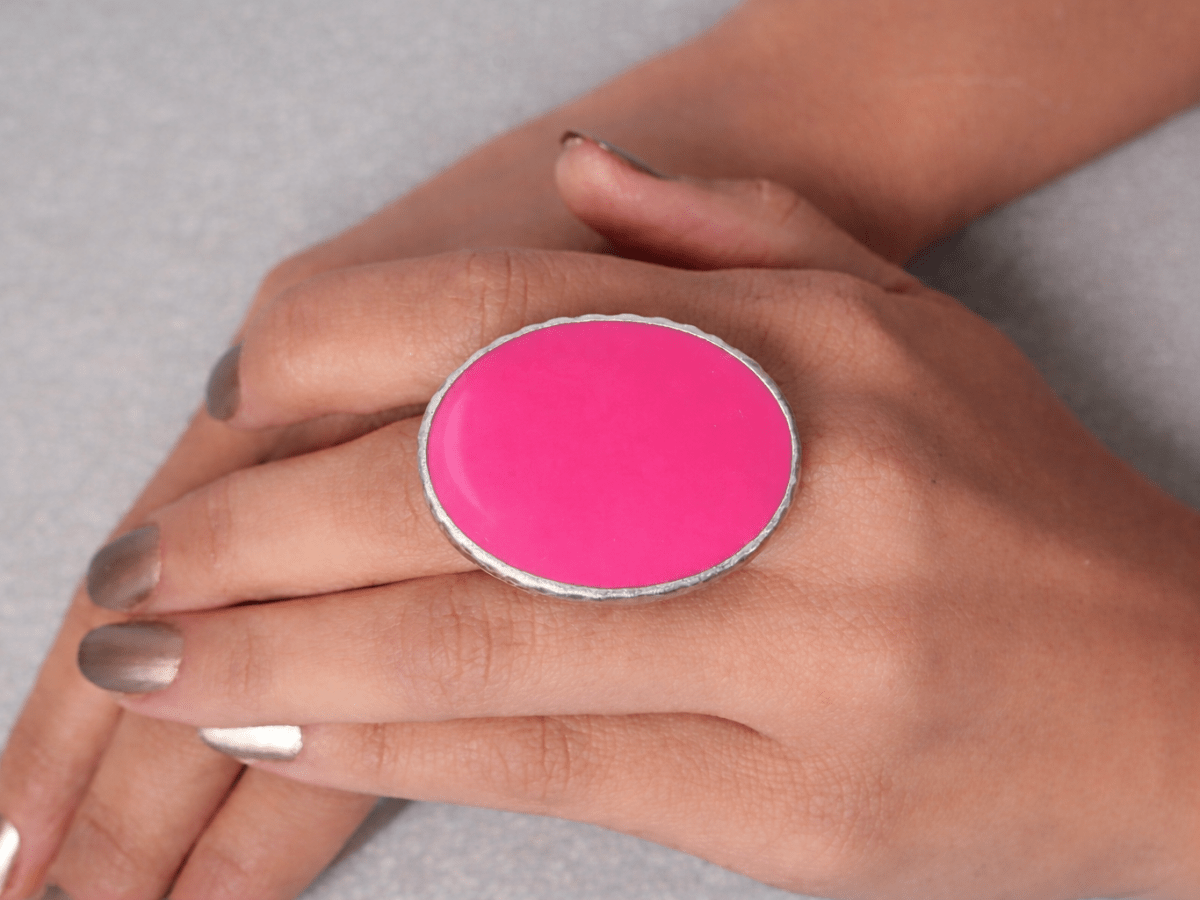 A models hand wearing a deep pink oval ring