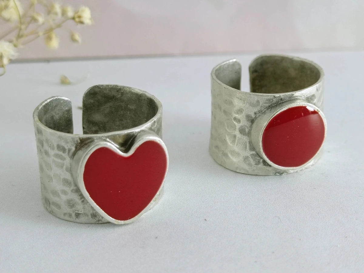 A picture of 2 bands rings, one with a red heart one with a red circle