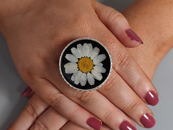 a pressed white daisy black ring on a models hand