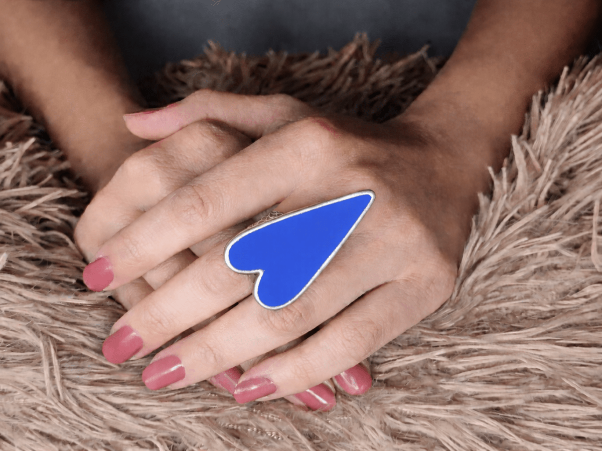 A models hand wearing a large blue heart shaped ring