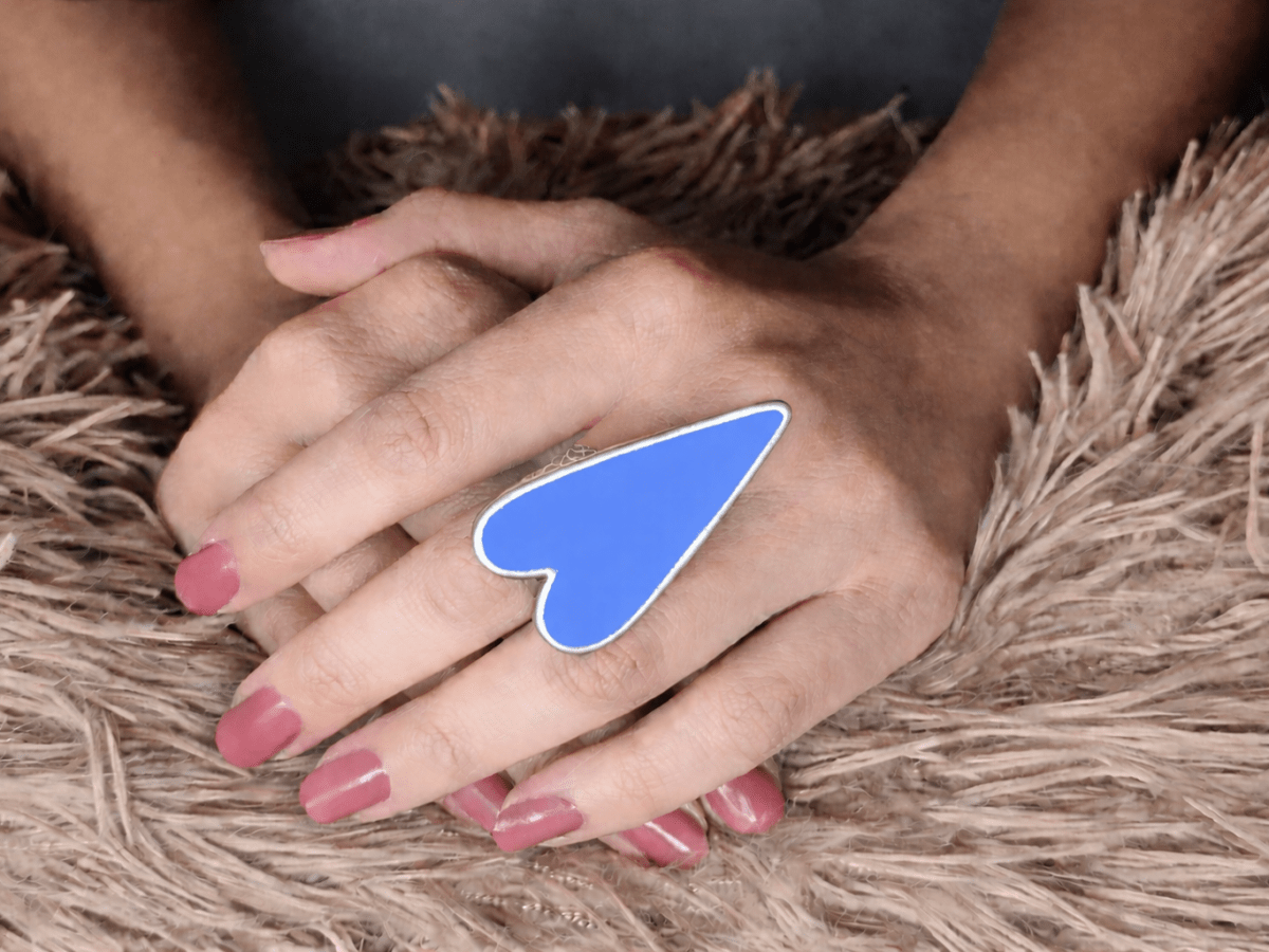 A models hand wearing a large pale blue heart shaped ring