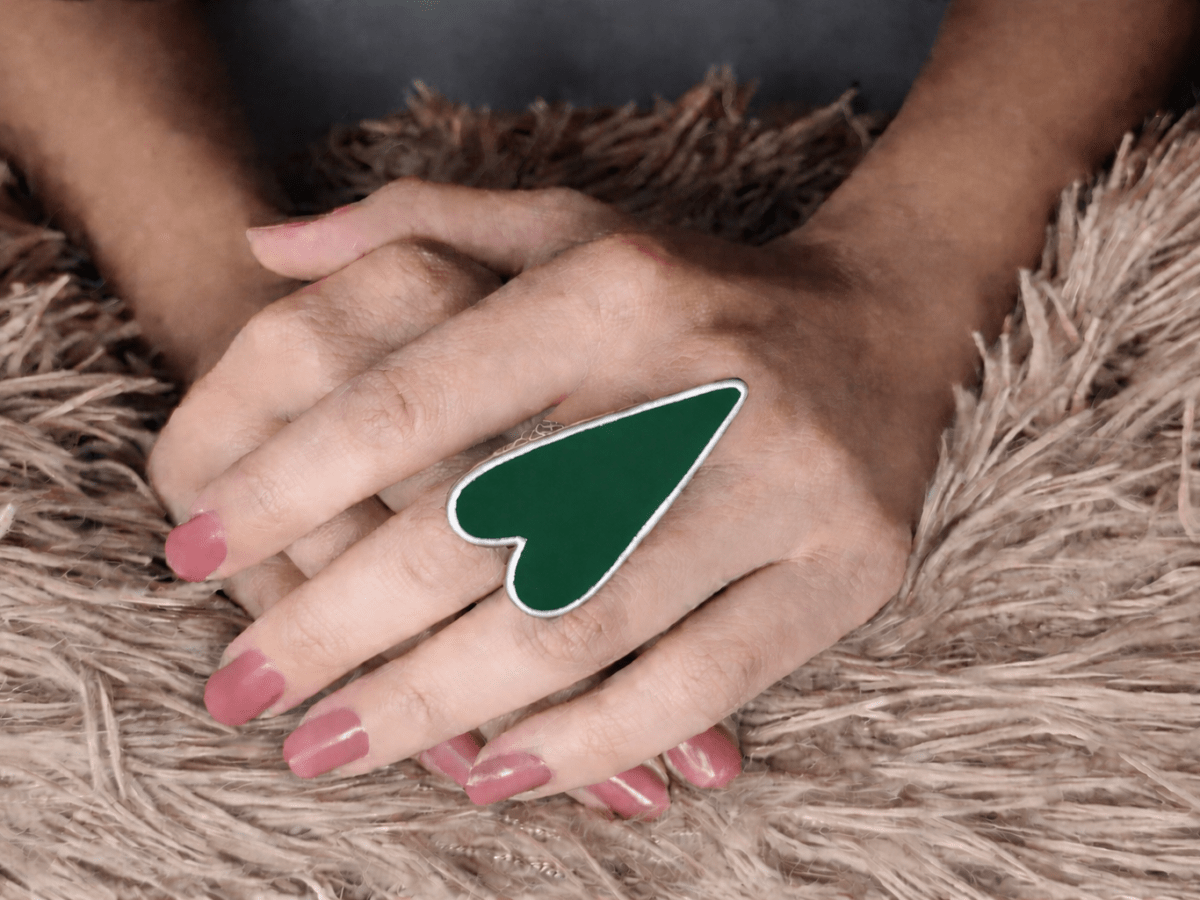 A models hand wearing a large dark green heart shaped ring