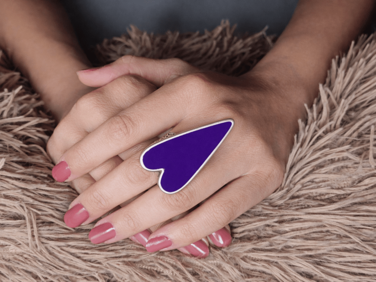A models hand wearing a large purple heart shaped ring