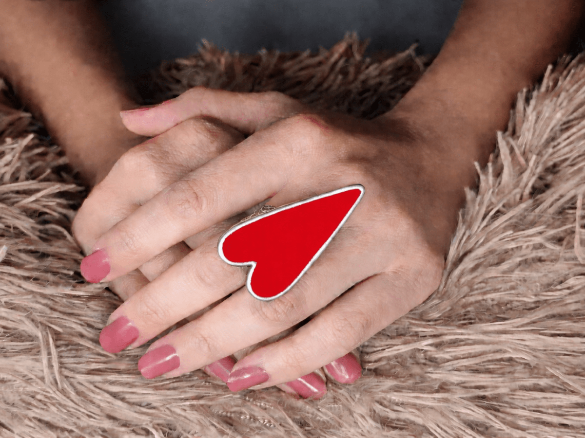 A models hand wearing a large red heart shaped ring