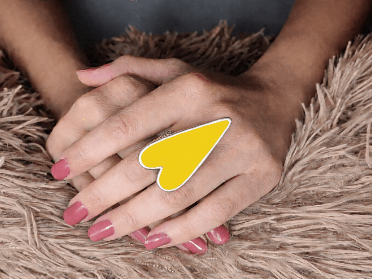 A models hand wearing a large yellow heart shaped ring