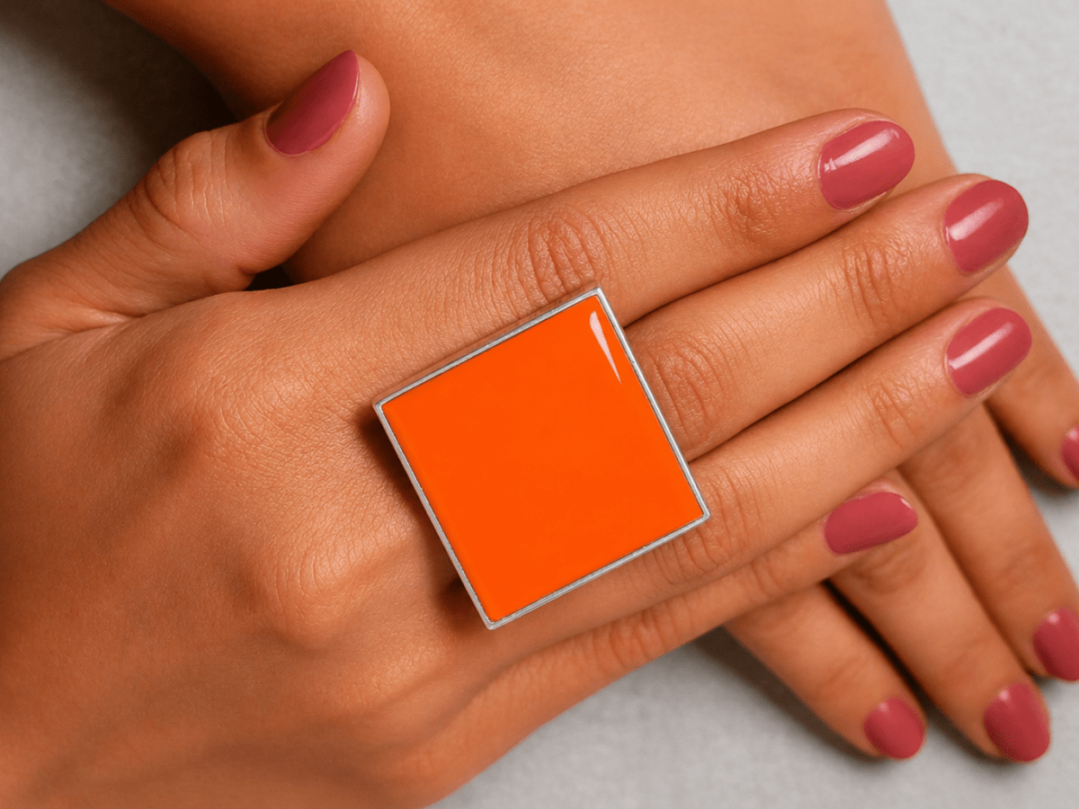  models hand wearing a bright neon orange square ring