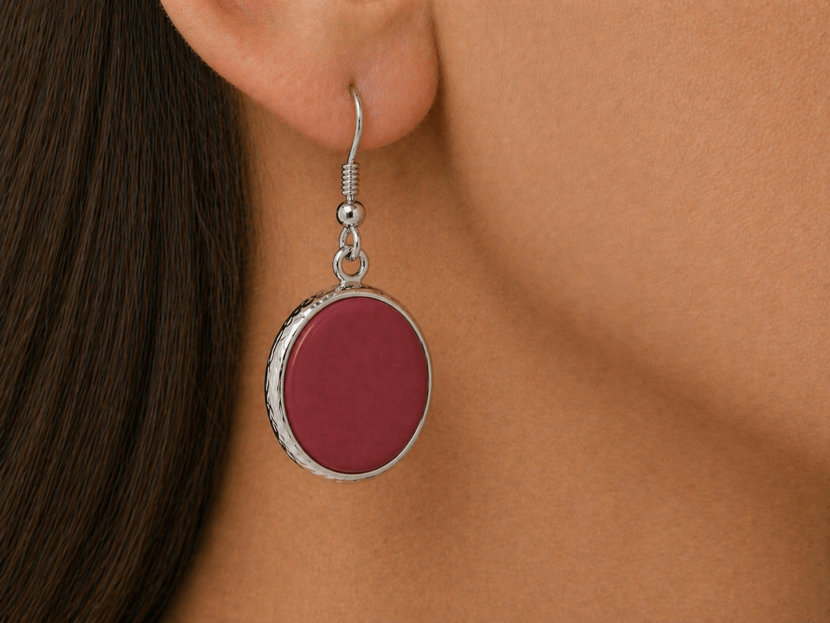 A model wearing some round dark red dangle drop earrings