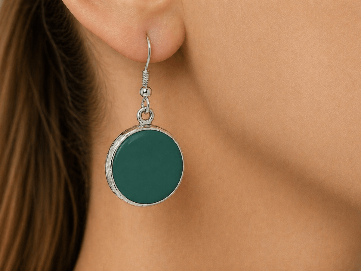 A model wearing some round dark green dangle drop earrings