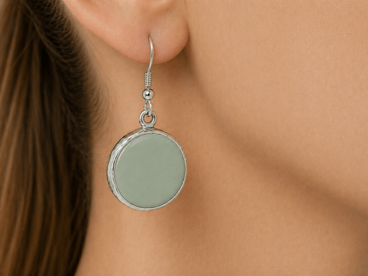 A model wearing some round sage green dangle drop earrings