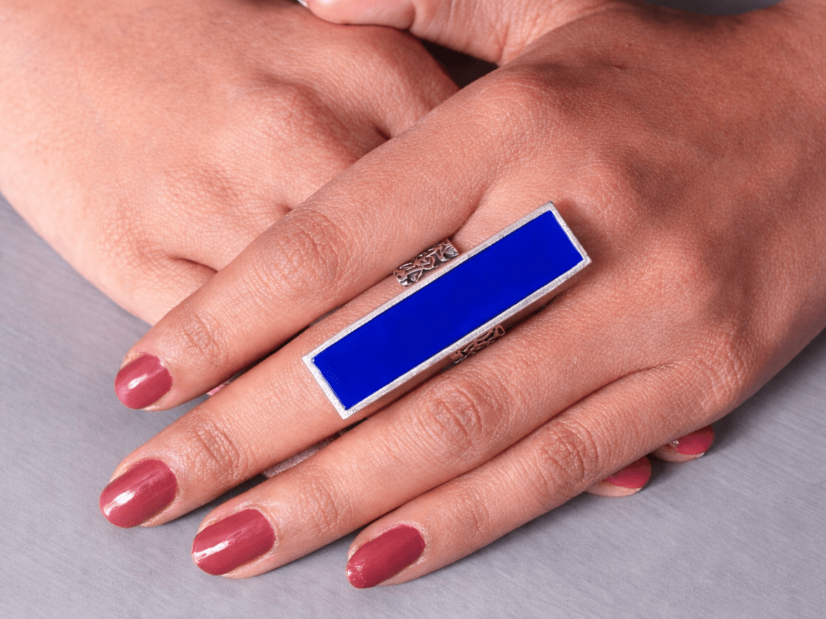 A models hand wearing a long slim blue ring