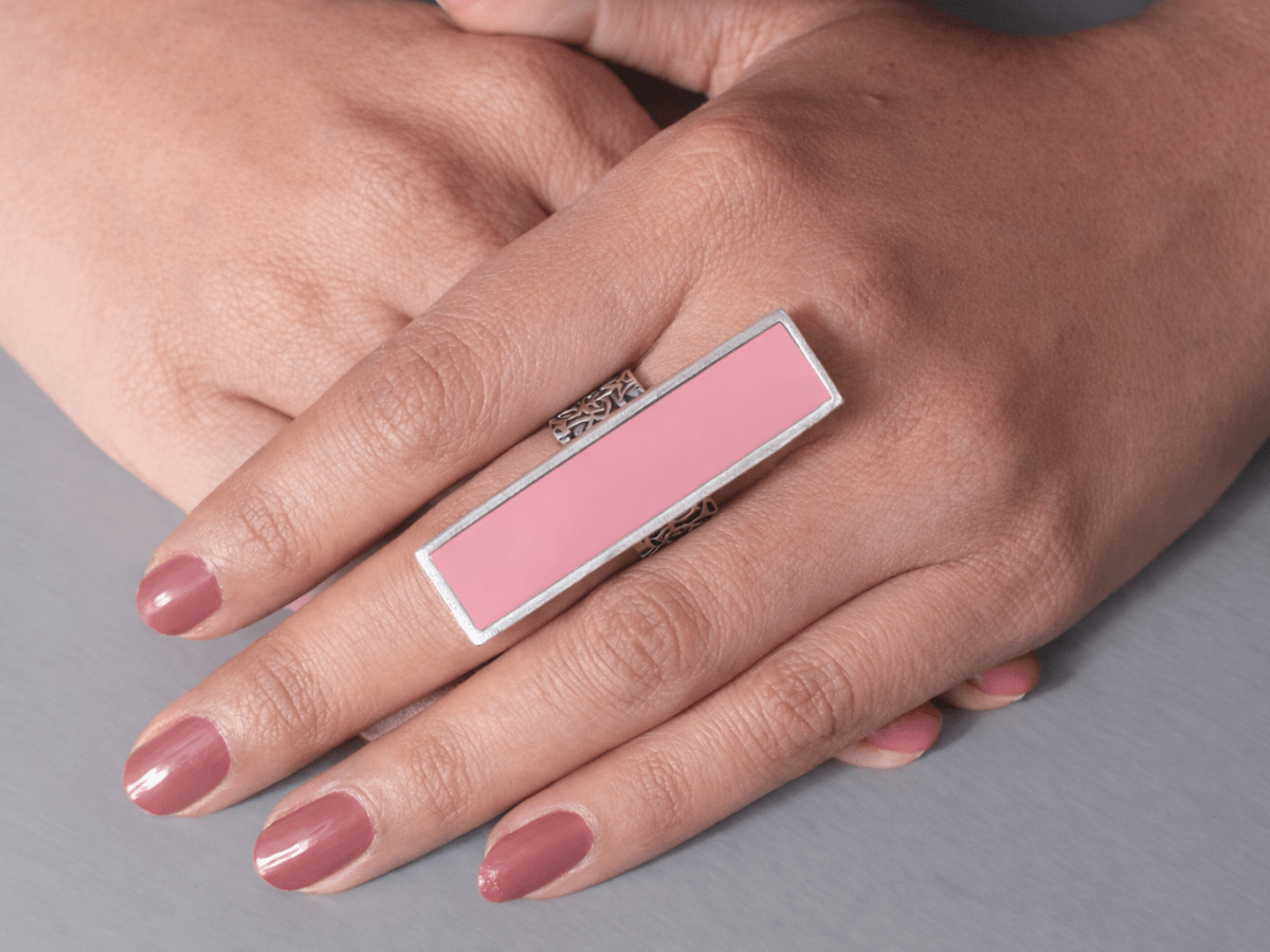 A models hand wearing a long slim pale pink ring