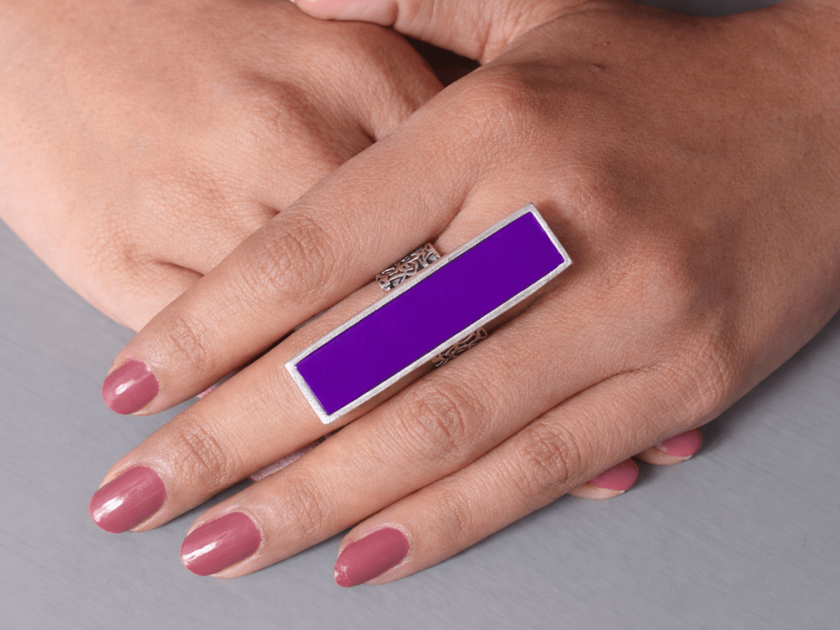 A models hand wearing a long slim purple ring