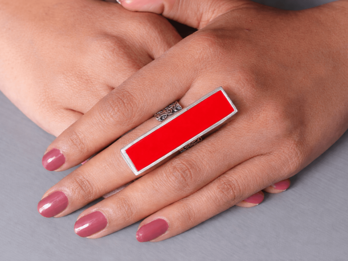 A models hand wearing a long slim red ring