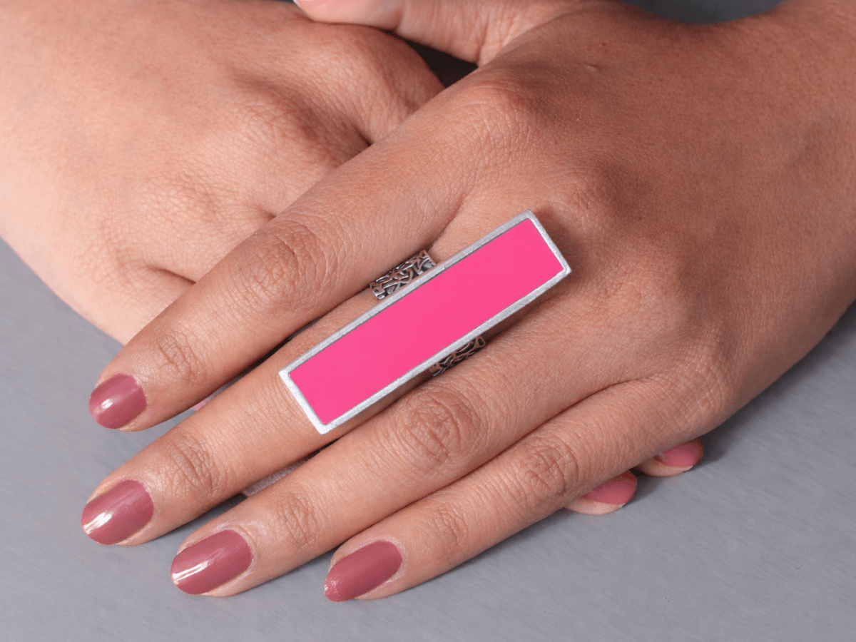 A models hand wearing a long slim deep pink ring