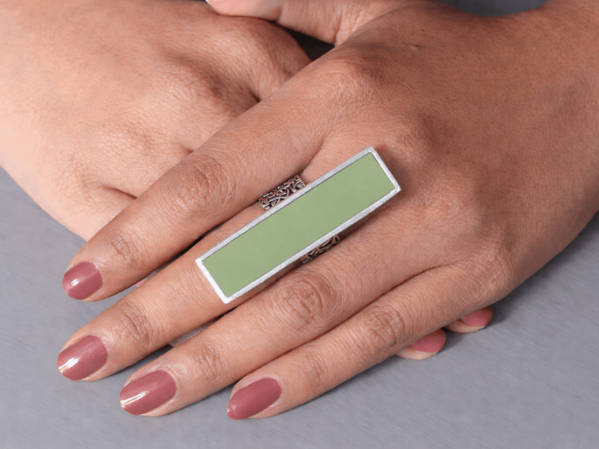 A models hand wearing a long slim sage green ring