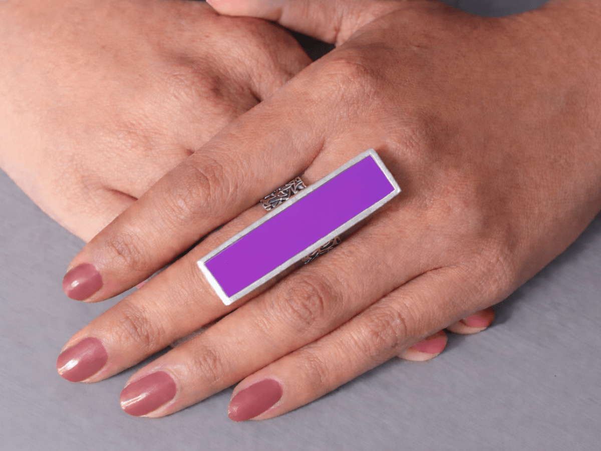 A models hand wearing a long slim violet ring