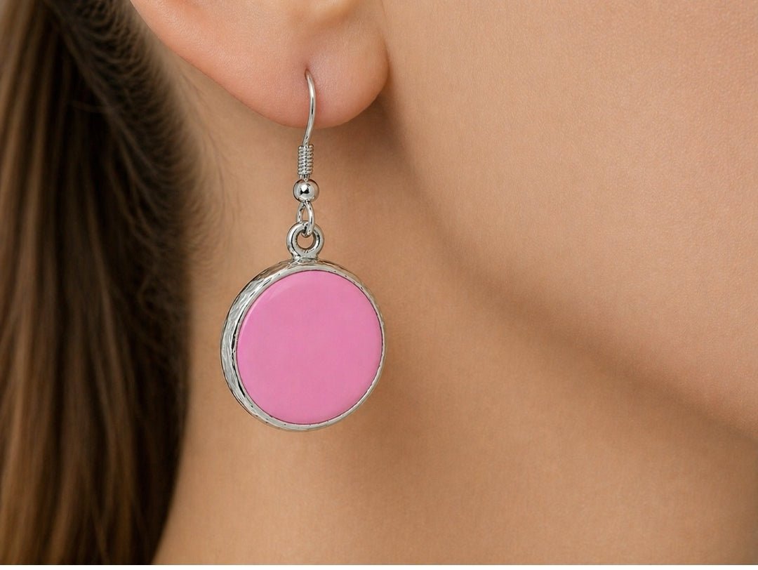 A model wearing some round pink dangle drop earrings