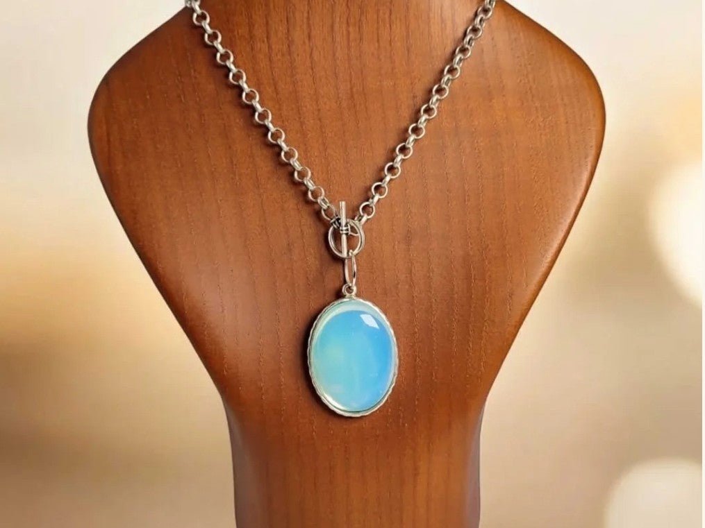 A moonstone pendant on a wooden bust