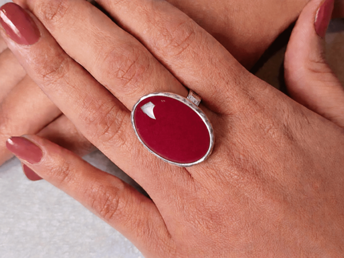 A models hands wearing a dark red ring