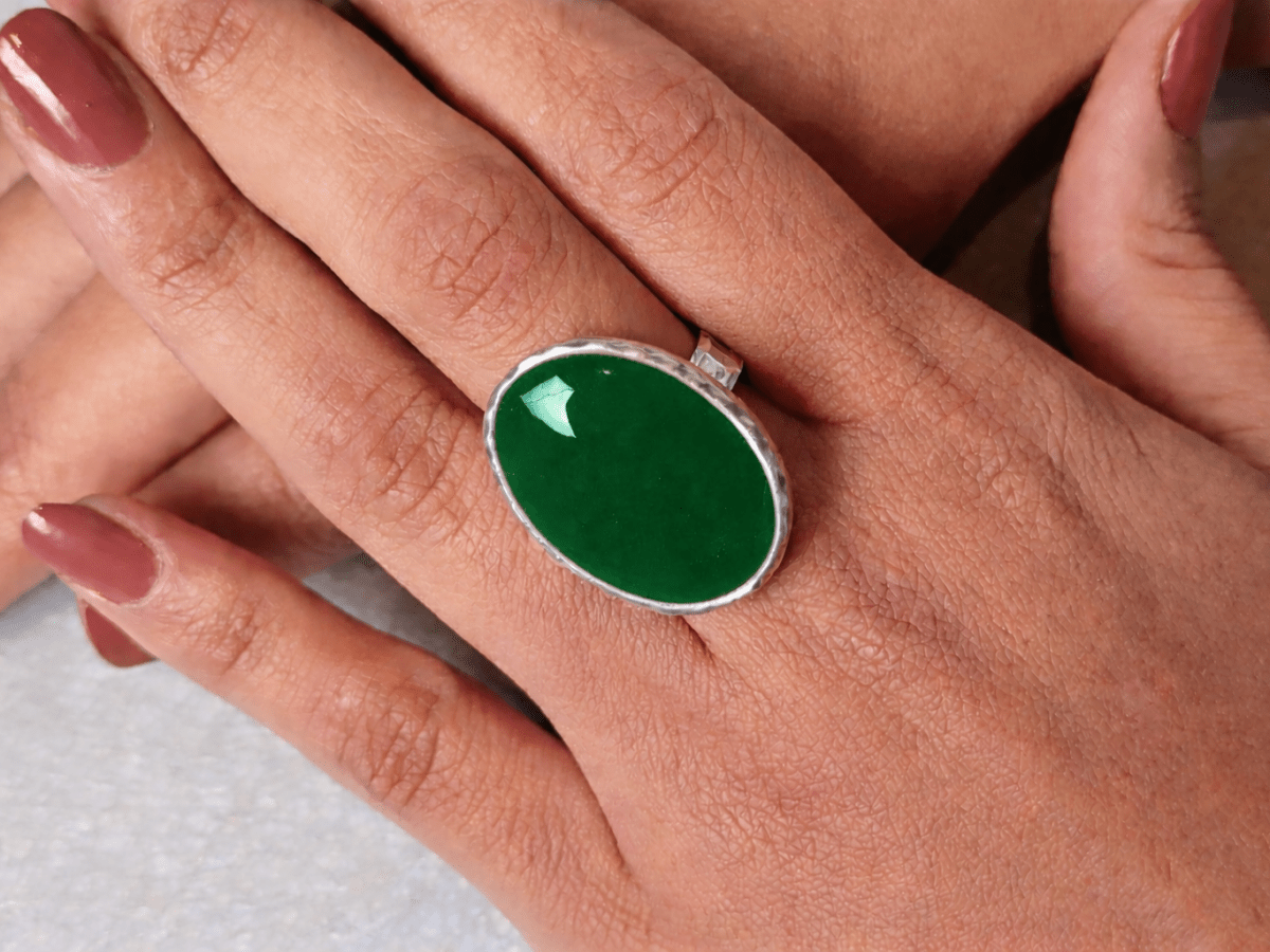 A models hands wearing a  dark green ring
