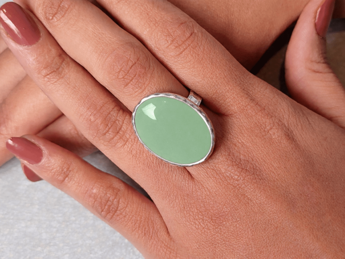 A models hands wearing a sage green ring
