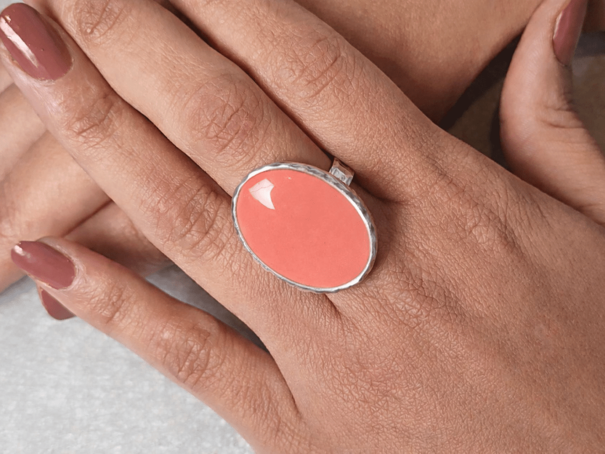 A models hands wearing a salmon pink ring