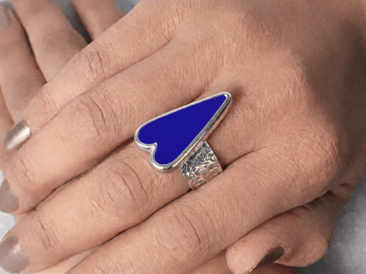 A models hands wearing a bright blue heart ring