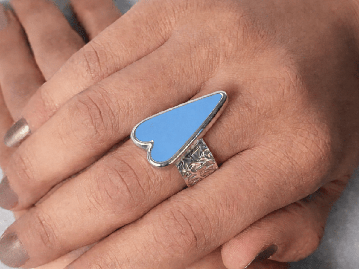 A models hands wearing a pale blue heart ring