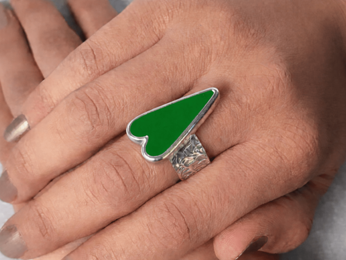 A models hands wearing a green heart ring
