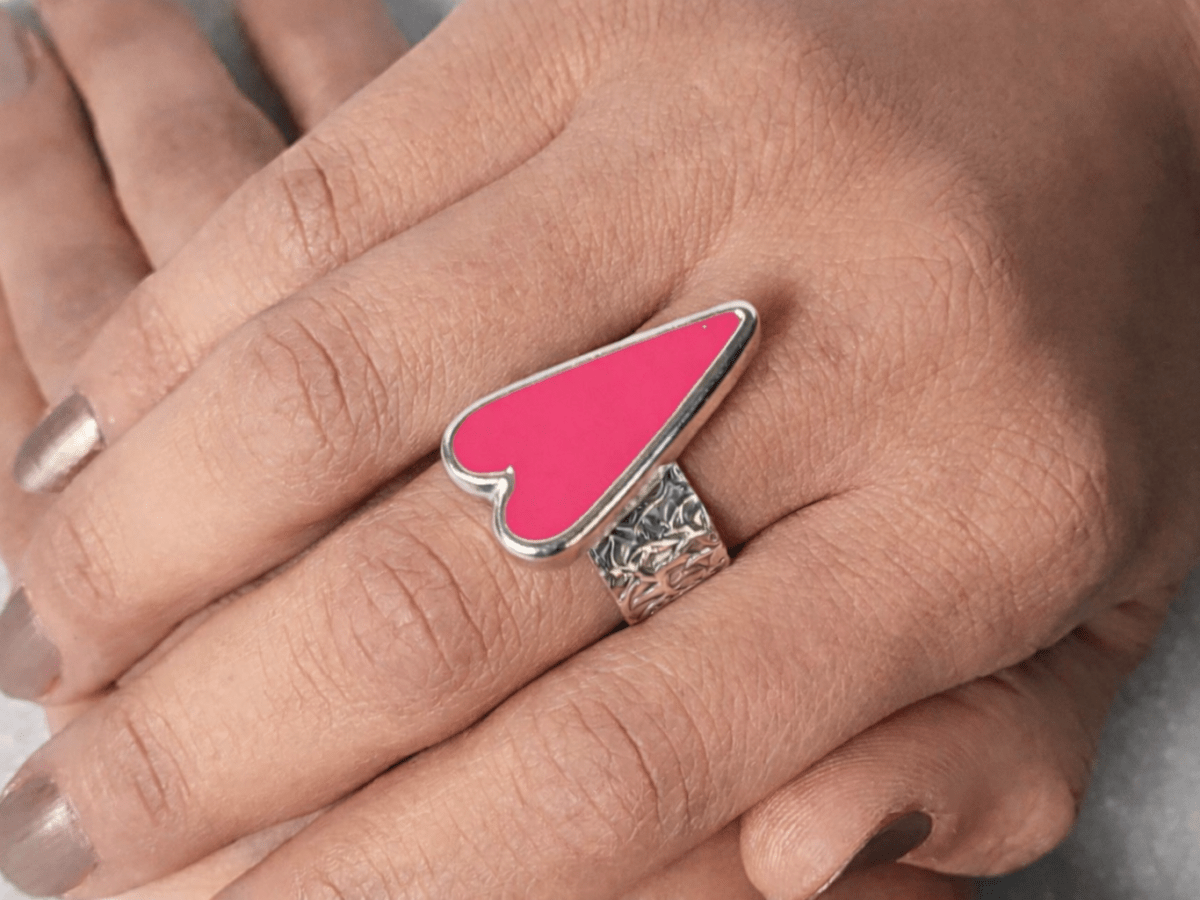 A models hands wearing a deep pink heart ring