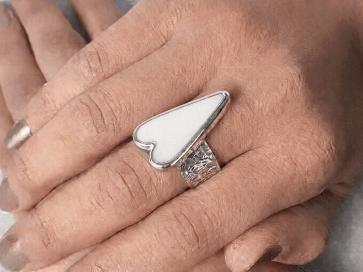 A models hands wearing a white heart ring