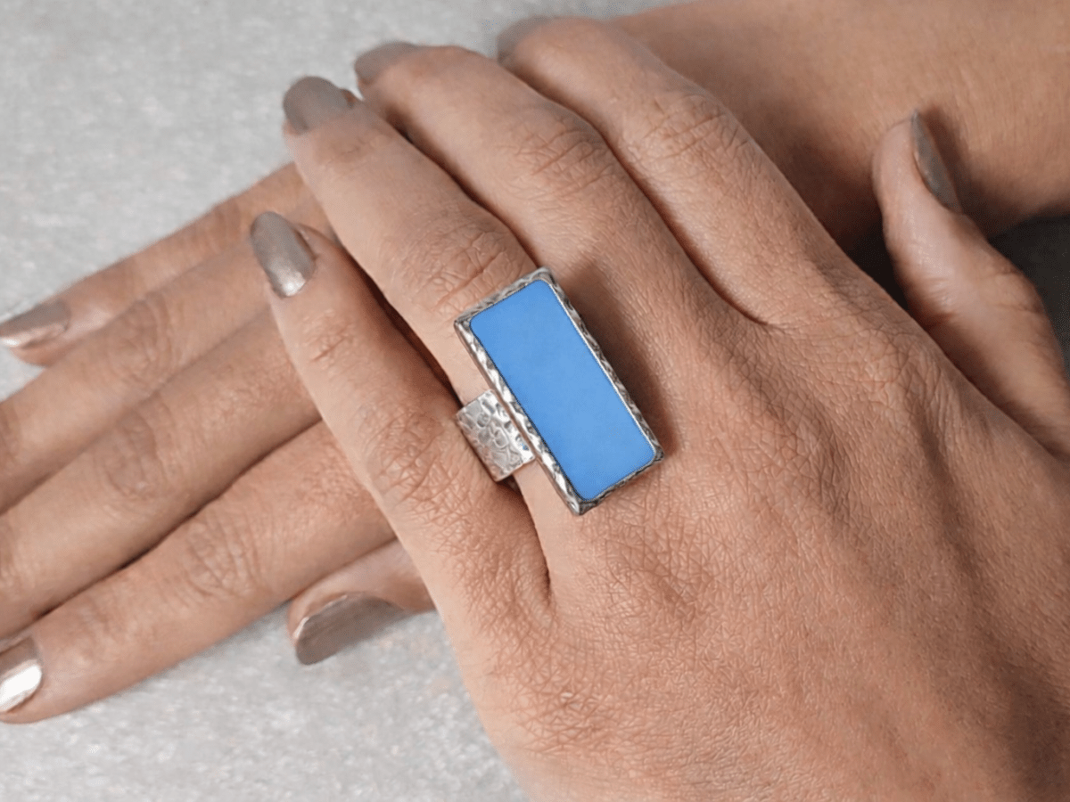 A models hand wearing a rectangular blue ring