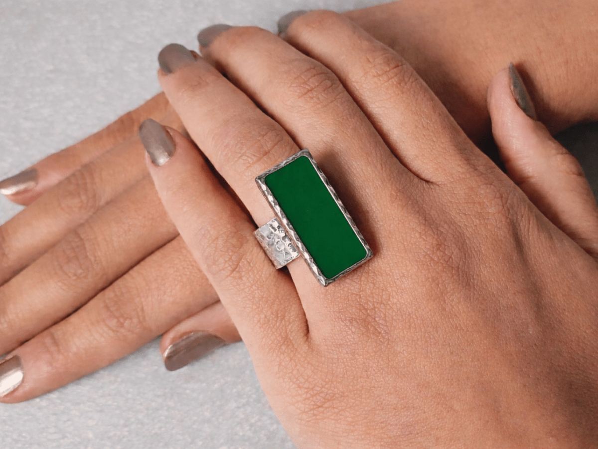 A models hand wearing a rectangular green ring