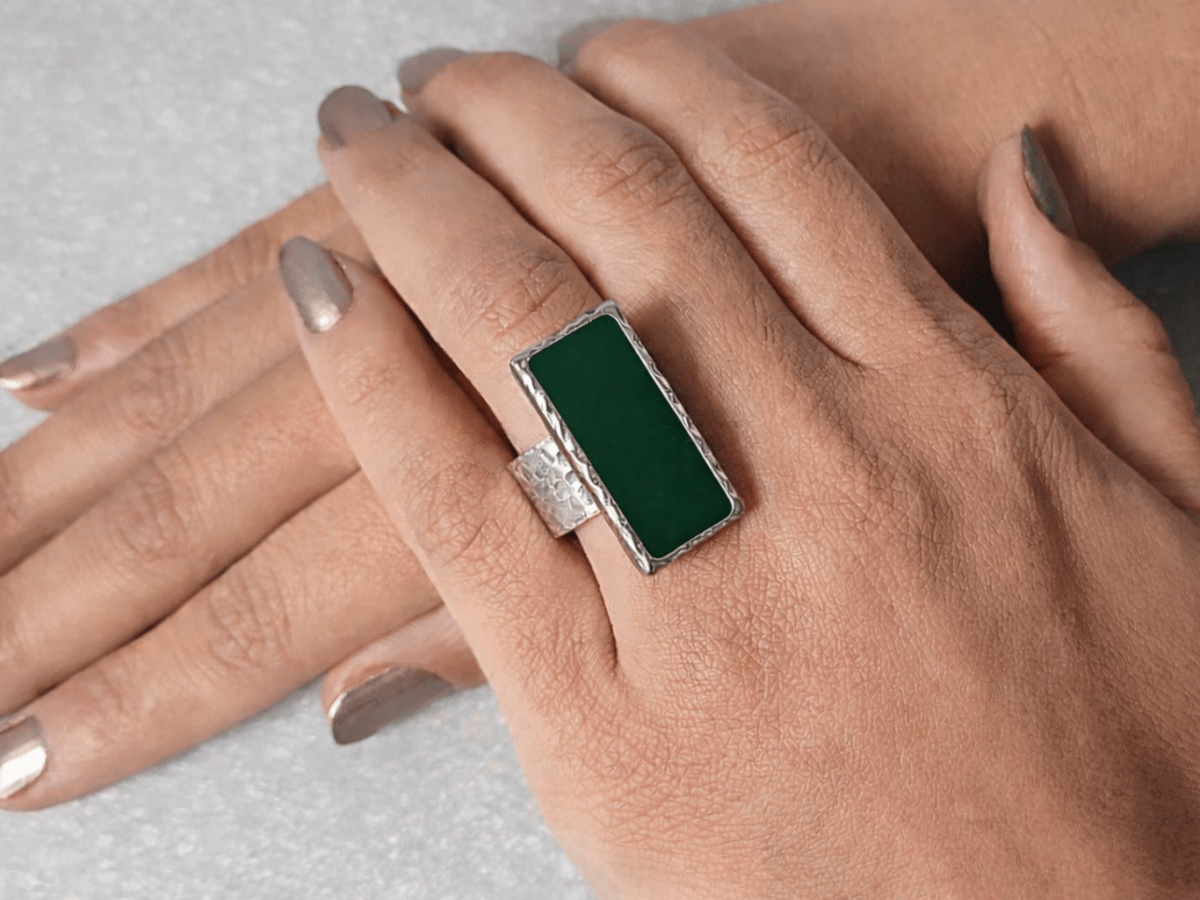 A models hand wearing a rectangular dark green ring