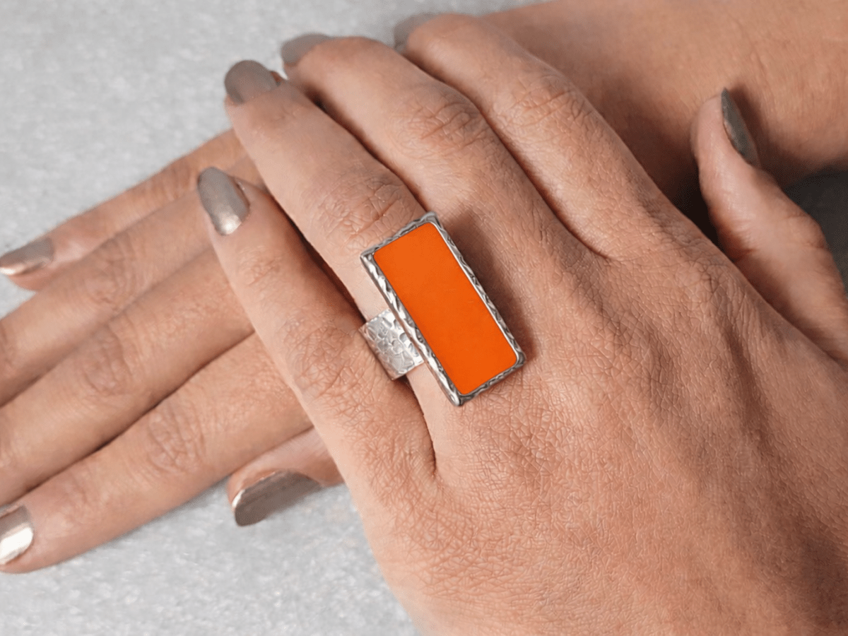 A models hand wearing a rectangular orange ring