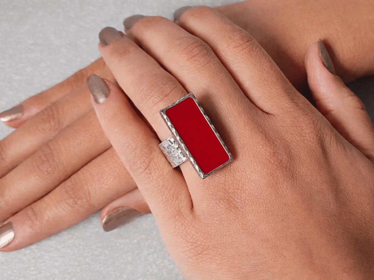A models hand wearing a rectangular red ring