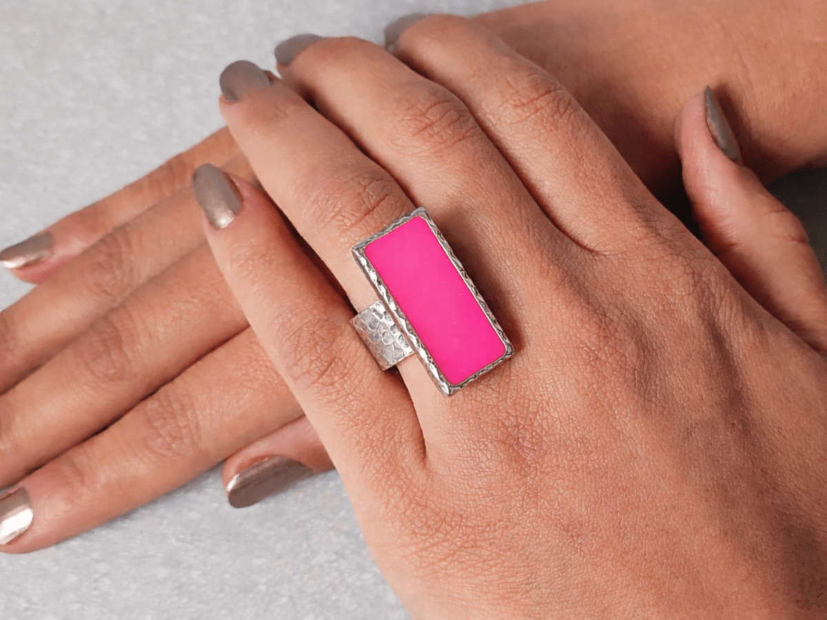 A models hand wearing a rectangular deep pink ring