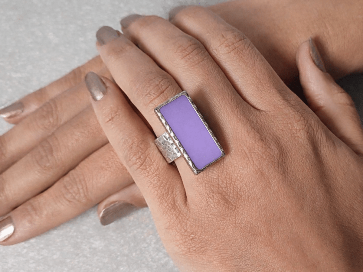 A models hand wearing a rectangular violet ring