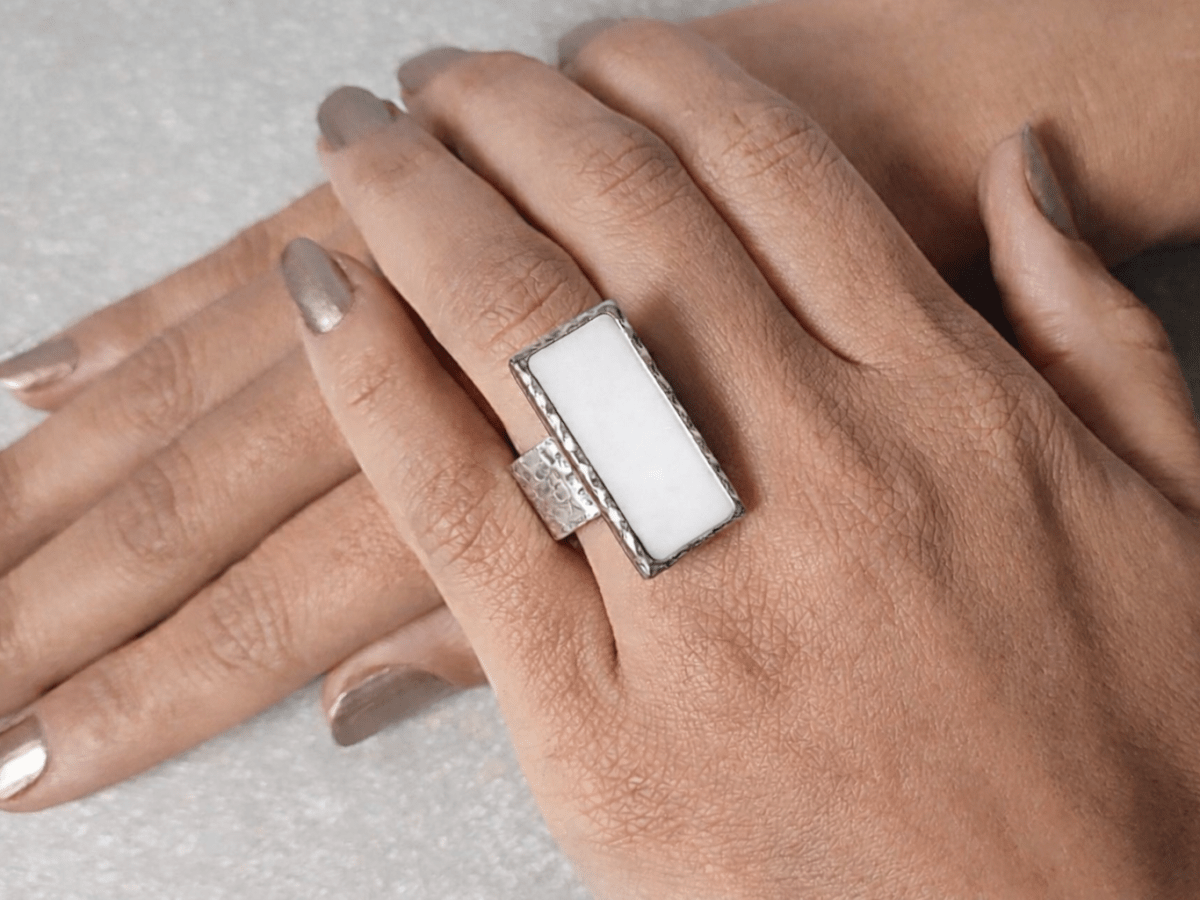 A models hand wearing a rectangular white ring