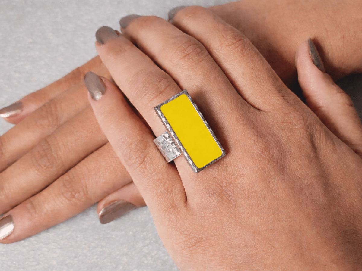 A models hand wearing a rectangular yellow ring