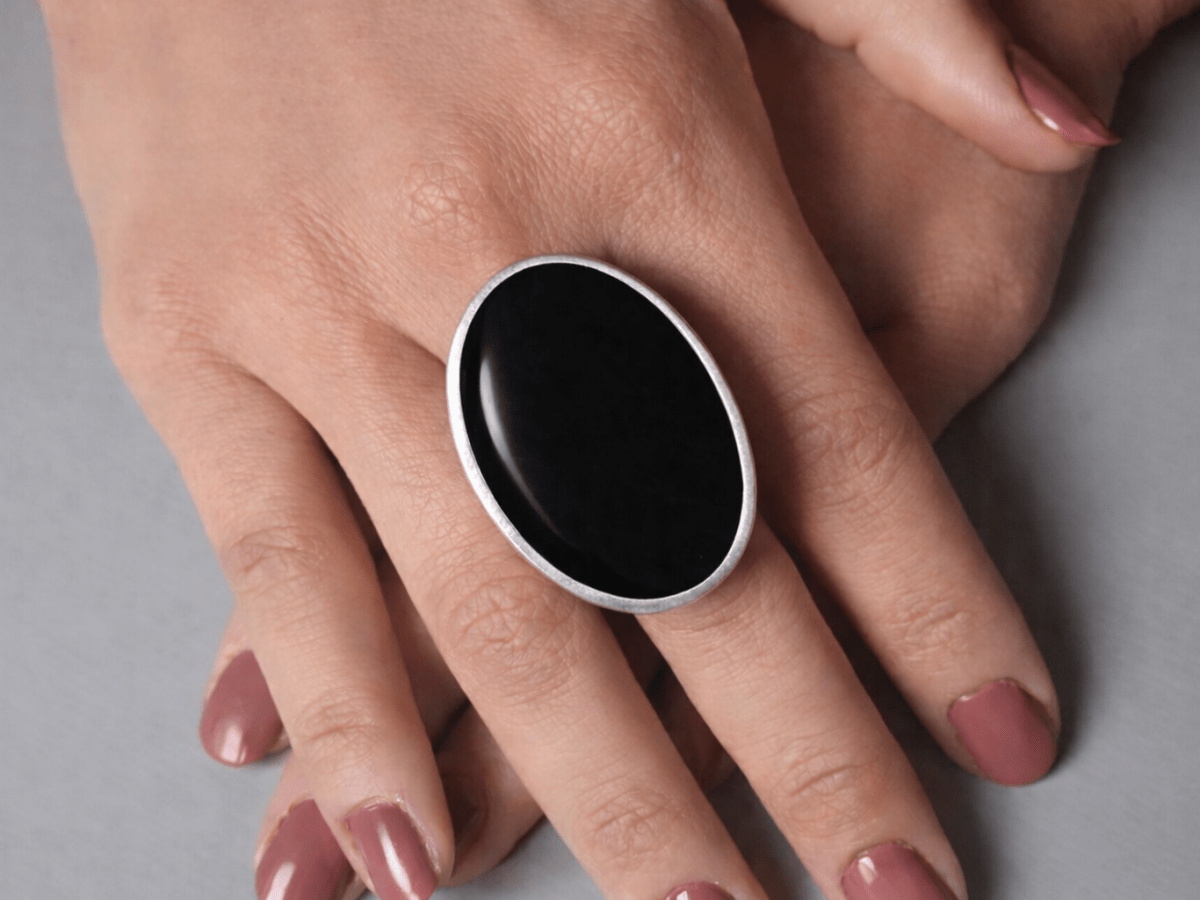 A models hands wearing a large black oval ring