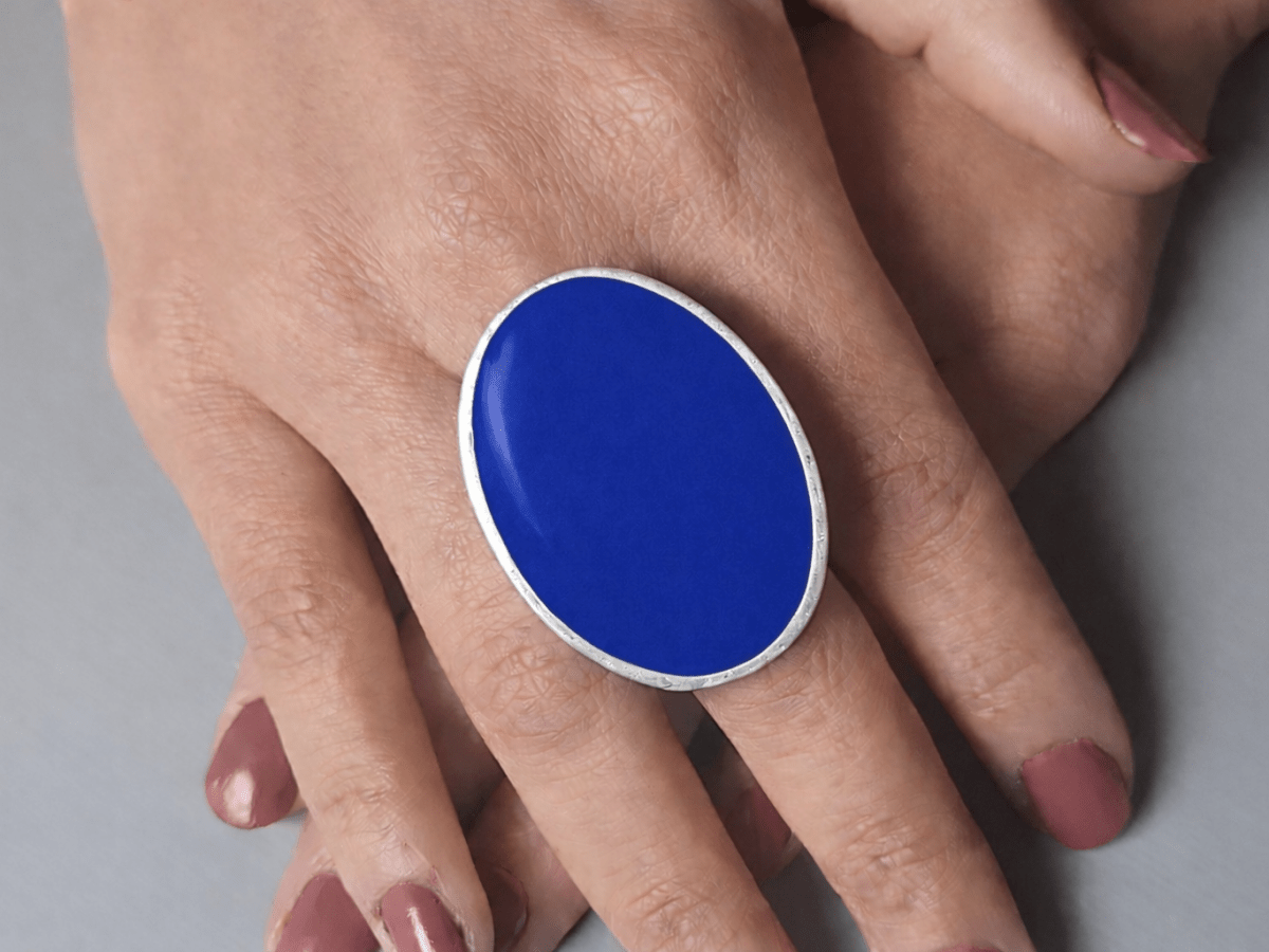 A models hands wearing a large bright blue oval ring