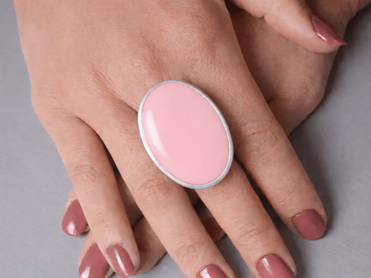 A models hands wearing a large pale pink oval ring