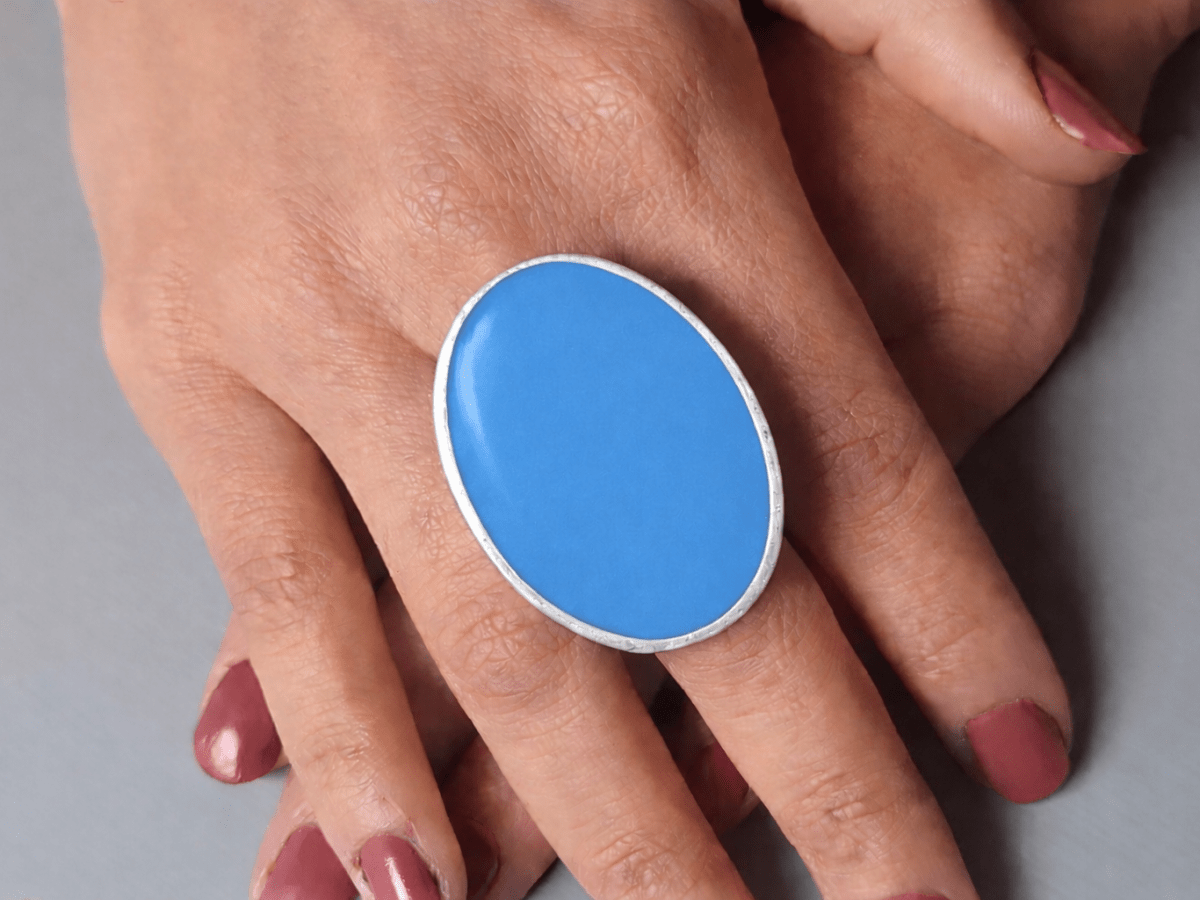 A models hands wearing a large blue oval ring