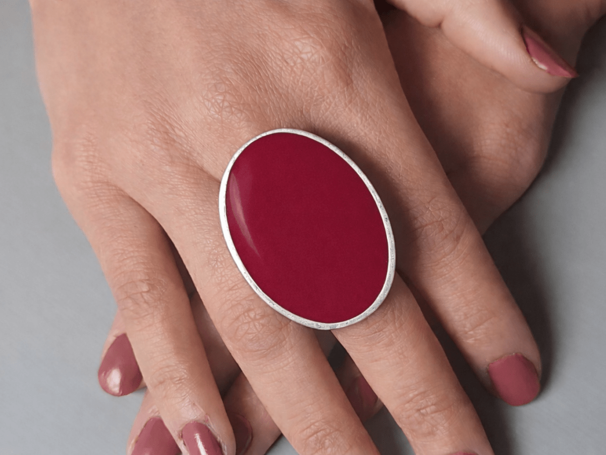A models hands wearing a large dark red oval ring