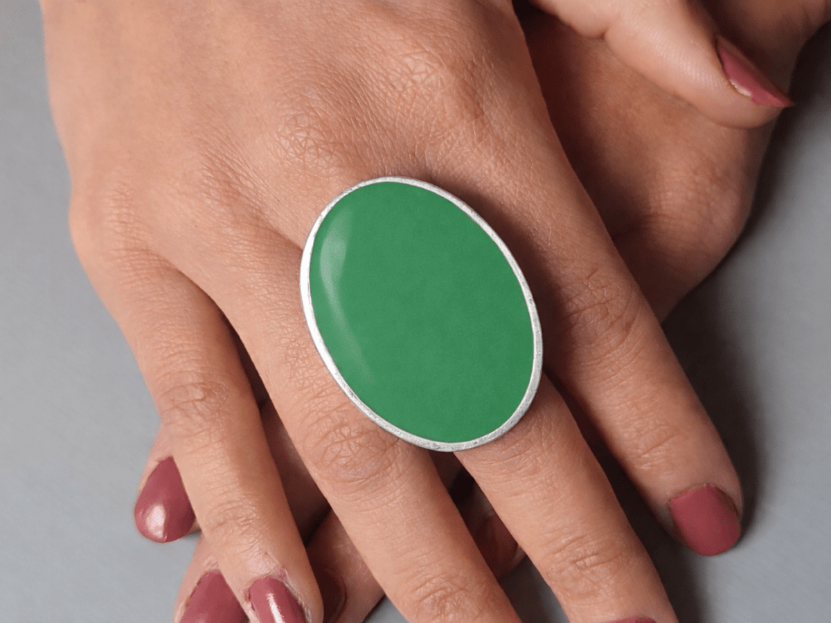 A models hands wearing a large green oval ring