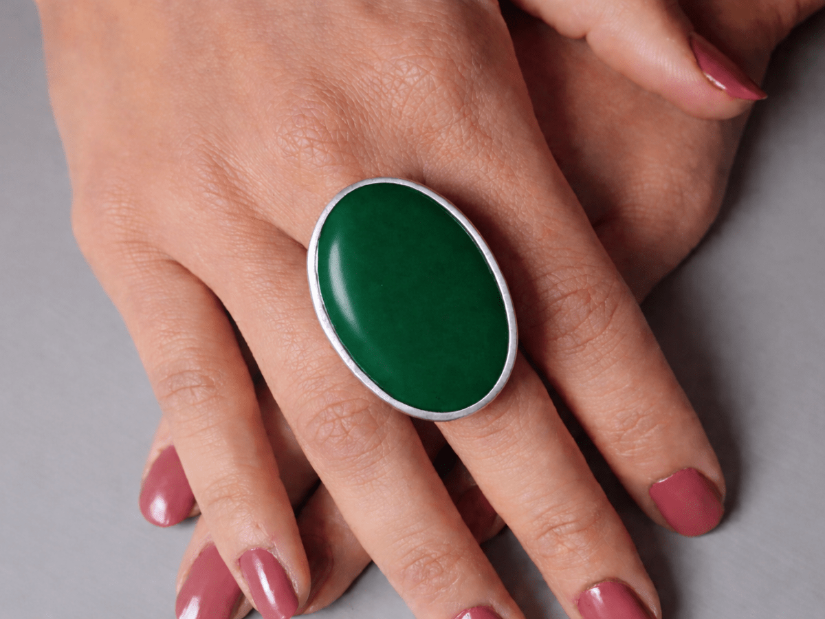 A models hands wearing a large dark green oval ring