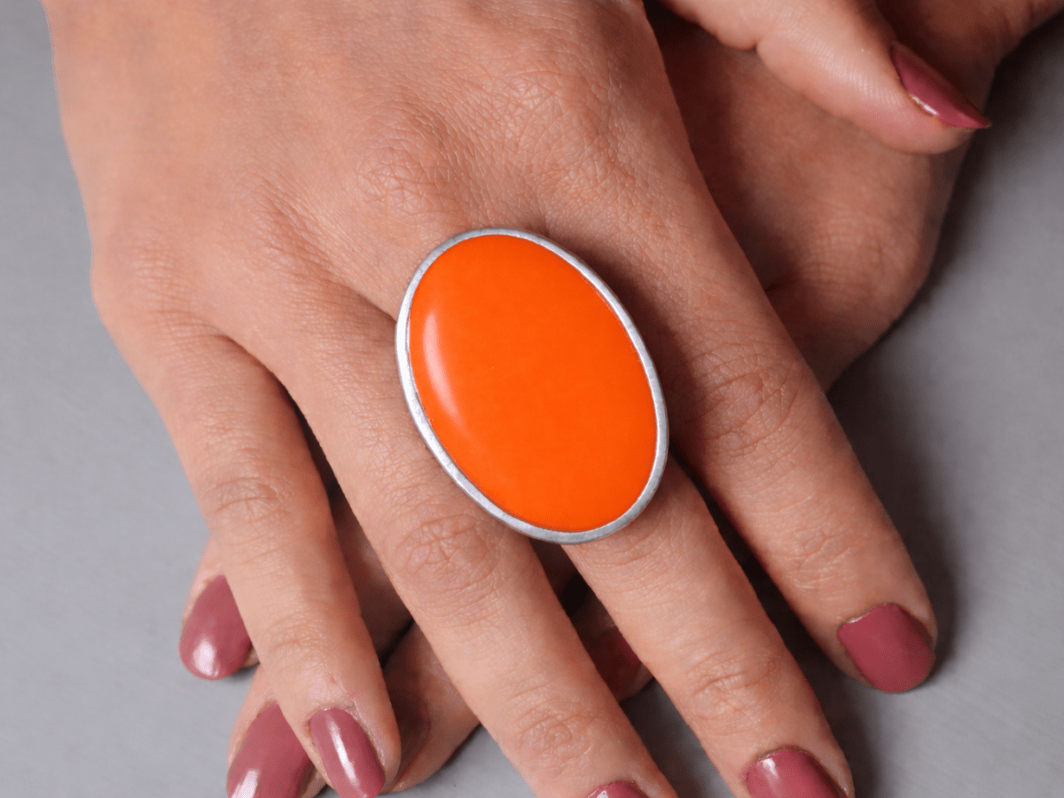 A models hands wearing a large orange oval ring
