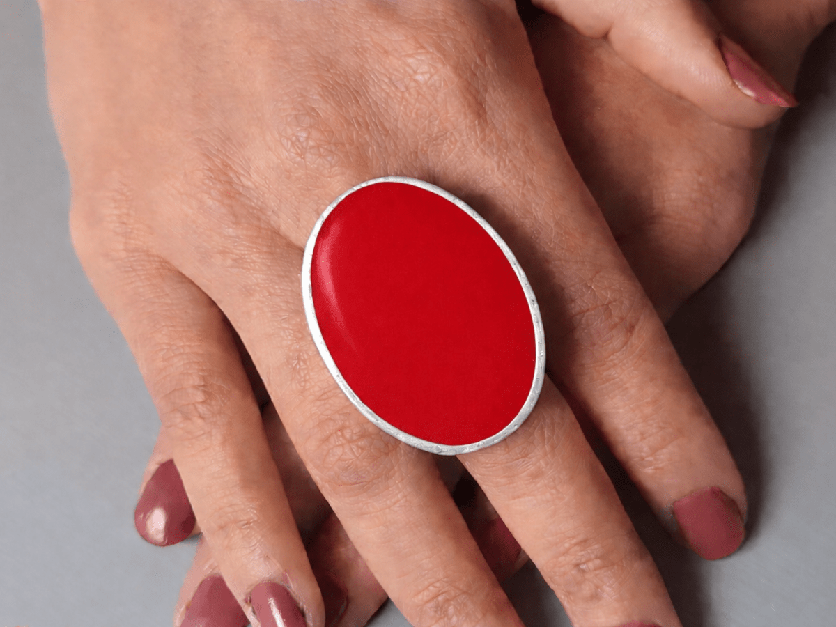 A models hands wearing a large red oval ring